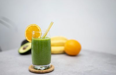 a green smoothie with an orange slice and a straw